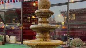 A stone fountain with water flowing, surrounded by a green artificial turf area. - Petra Aretas Hotel (Wadi Musa)
