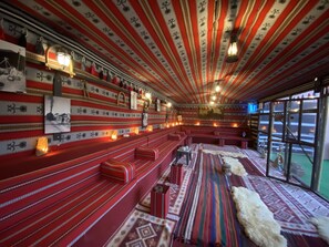 A room with red benches, patterned walls, and a fur rug. - Petra Aretas Hotel (Wadi Musa)