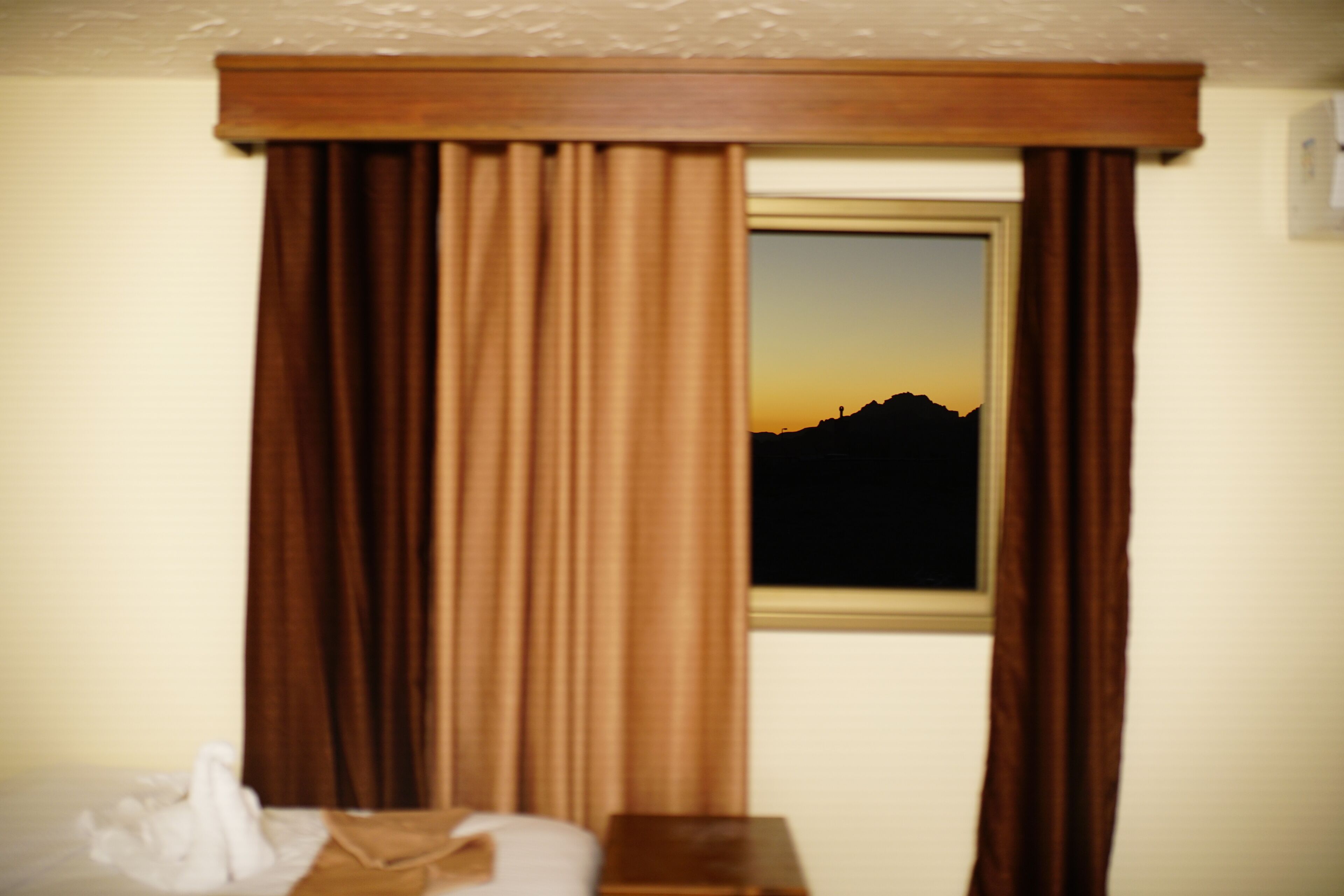 Une chambre d’hôtel avec un lit, une table de chevet et une fenêtre avec des rideaux.
