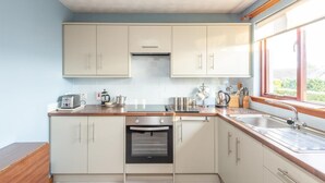 Una cocina moderna con armarios blancos, horno empotrado y ventana que aporta luz natural.