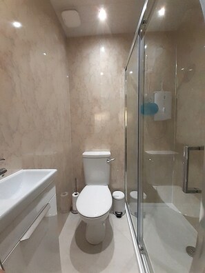 A modern bathroom with a toilet, sink, and glass-enclosed shower. - 2 Bed Home With Private Garden in the Highlands (Beauly)