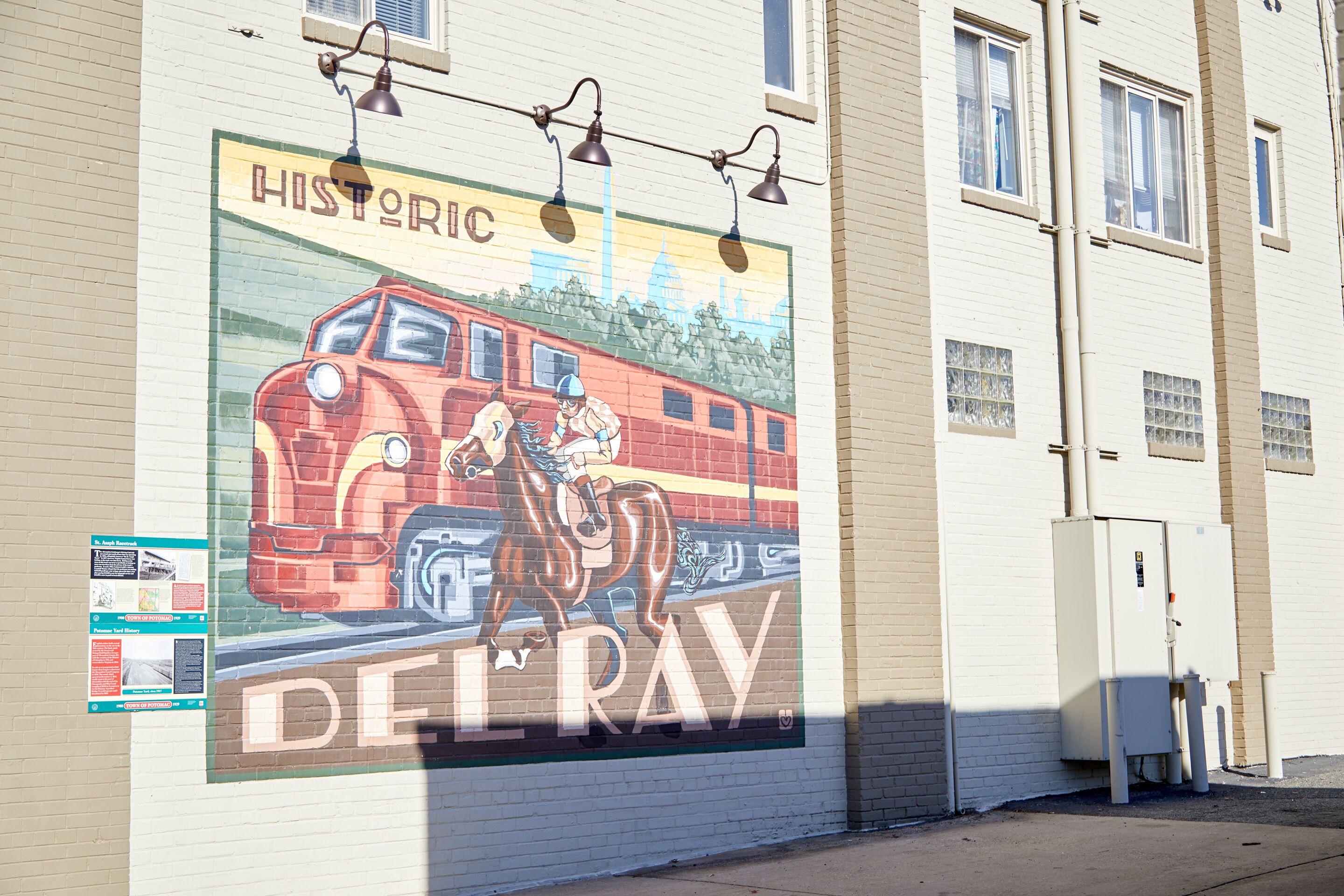 A mural on a building wall depicting a red train and a horse.