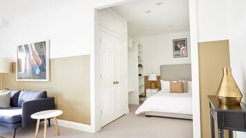 A hotel room with a bed, a sofa, a small table, a wardrobe, and a painting on the wall.