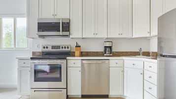 A modern kitchen with white cabinets, stainless steel appliances including an oven, microwave, and dishwasher, and a granite countertop.
