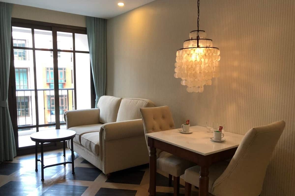 A modern living room with a sofa, a round table, and a chandelier.