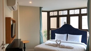 Une chambre d’hôtel avec un grand lit, un téléviseur fixé au mur et une fenêtre ornée de barreaux en fer décoratifs.