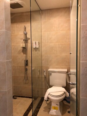 A glass-enclosed shower stall with a handheld showerhead and a toilet visible through the glass. - Espana Condo Pattaya By JC (Pattaya)