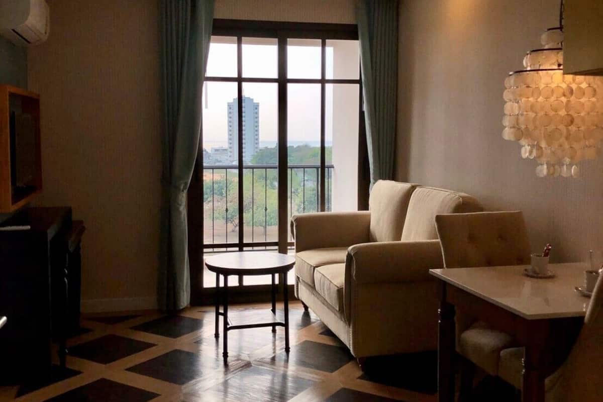 A living room with a sofa, a dining table, and a view of a building through large windows.