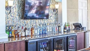 A bar area with a television mounted on the wall, a variety of liquor bottles, and a minibar with a glass display. - Tideview 166 · NEW Ultra Modern & Super Clean 3 Full Suites (Orlando)