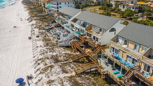 A beachfront hotel with multiple-story buildings, outdoor seating areas, and a beach access walkway. - Beautiful Beachfront 4BR Green Reef townhome with Ocean Views! (Destin)