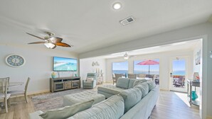 A spacious living room with a large sectional sofa, a television, and a ceiling fan. - Beautiful Beachfront 4BR Green Reef townhome with Ocean Views! (Destin)