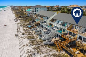 A beachfront hotel with multiple balconies, a boardwalk, and a beach view.