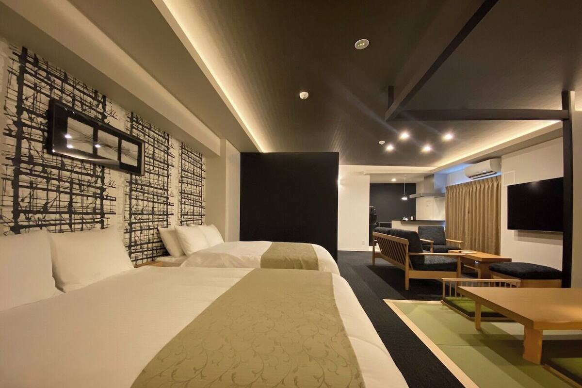 A hotel room with a large bed, a seating area with a table, and a TV.
