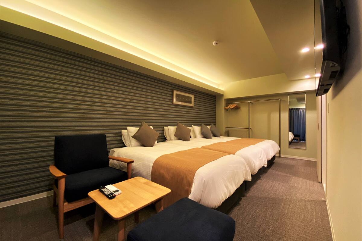 A hotel room with a large bed, a desk, a chair, and a TV.