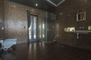 A modern bathroom with a glass shower enclosure, a white sink, and a tiled wall.