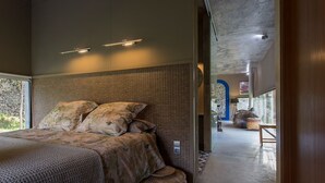 A modern bedroom with a large bed, woven headboard, and a view of the outdoors.