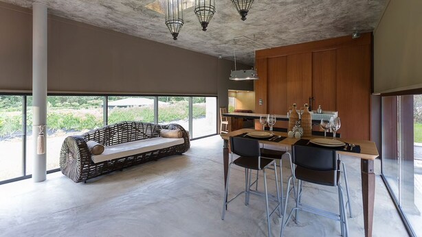 A modern kitchen with a dining area, large windows, and a unique ceiling design.