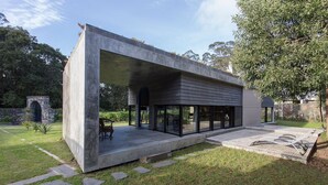 A modern house with a large open patio, a stone archway, and a minimalist design.