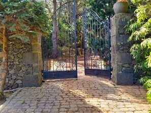 A stone pathway leading to a wrought iron gate. - Villa with modern minimalist architecture in the middle of a nature reserve (Rabo de Peixe, Sao Miguel Island, Azores)