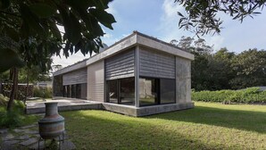 A modern house with a flat roof, large windows, and a concrete exterior.
