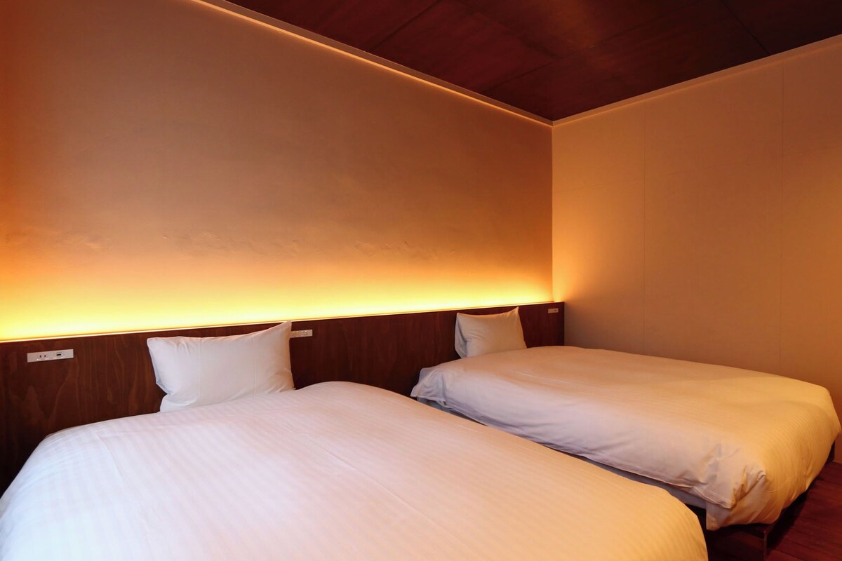 Una habitación de hotel con dos camas, techo de madera y un espejo en la pared.