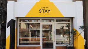A hotel entrance with a yellow and white facade, glass doors, and a sign reading "STAY Nirasaki Guide Hotel". - nirasakiyaSTAY (Nirasaki)