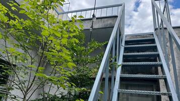 A metal staircase leading to a building's upper level, surrounded by greenery.