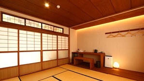 A traditional Japanese room with tatami flooring, shoji screens, a wooden desk, and a hanging clothes rack. - nirasakiyaSTAY (Nirasaki)