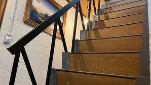 A wooden staircase with metal railings and a picture frame on the wall. - nirasakiyaSTAY (Nirasaki)