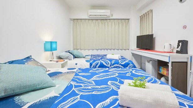 A hotel room with a bed, a desk, a TV, and an air conditioner. - FC House Shibuya 101 (Tokyo)