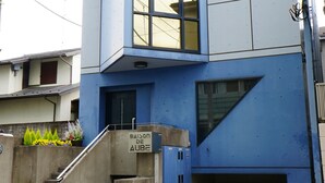 A modern building with a blue facade, a visible entrance, and a staircase leading to the ground level. - FC House Shibuya 101 (Tokyo)