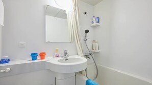 A bathroom with a white sink, mirror, shower, and a blue towel. - FC House Shibuya 101 (Tokyo)