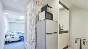 A compact hotel room with a bed, a refrigerator, a microwave, and a small kitchenette. - FC House Shibuya 101 (Tokyo)
