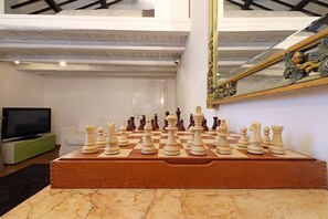 A chessboard set up on a marble table in a room with a high ceiling and a large mirror on the wall.