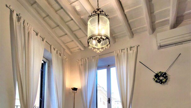 A dining room with a round table set for a meal, white chairs, and a chandelier. - Navona Loft Terrace, splendid apartment with terrace in the historic center (Roma)