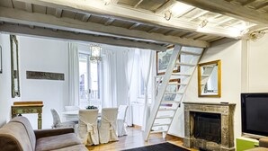 A living room with a fireplace, a TV, and a staircase leading to an upper floor. - Navona Loft Terrace, splendid apartment with terrace in the historic center (Roma)