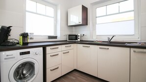 A compact kitchen with a washing machine, microwave, and a coffee maker. - Vacation breathing space in Greetsiel (Greetsiel)