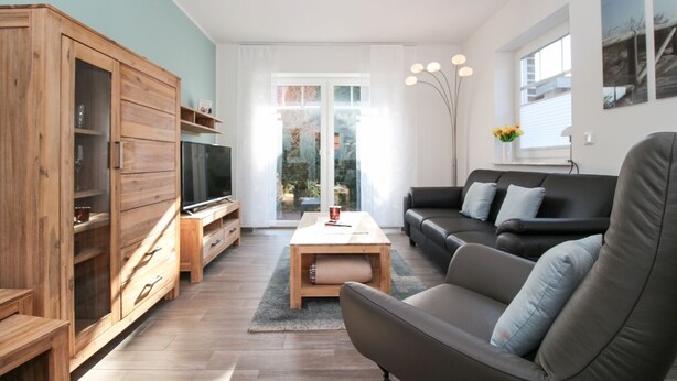 A modern living room with a wooden cabinet, a TV, a sofa, and a coffee table. - Vacation breathing space in Greetsiel (Greetsiel)