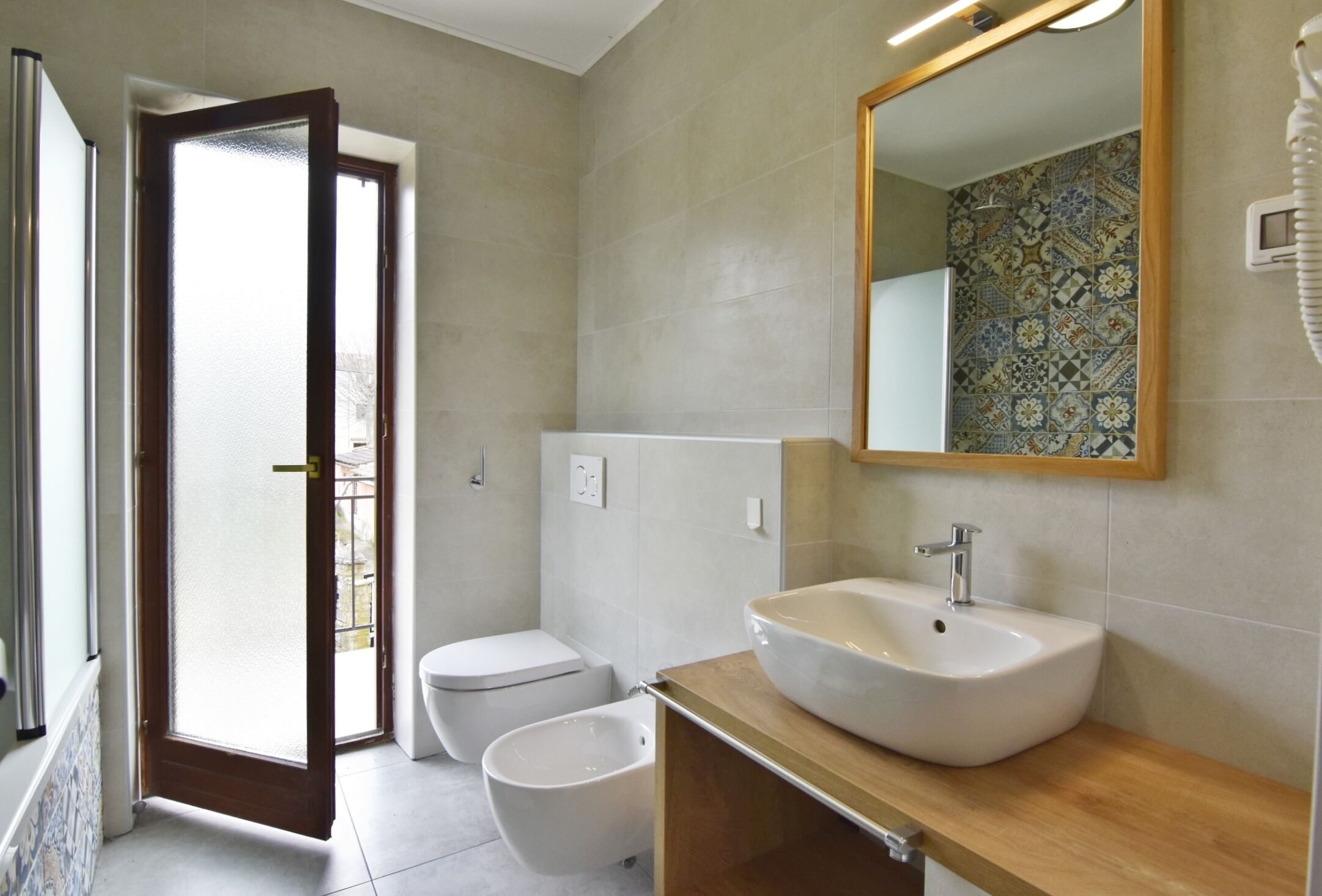 A bathroom with a toilet, bidet, and a sink with a mirror above it.