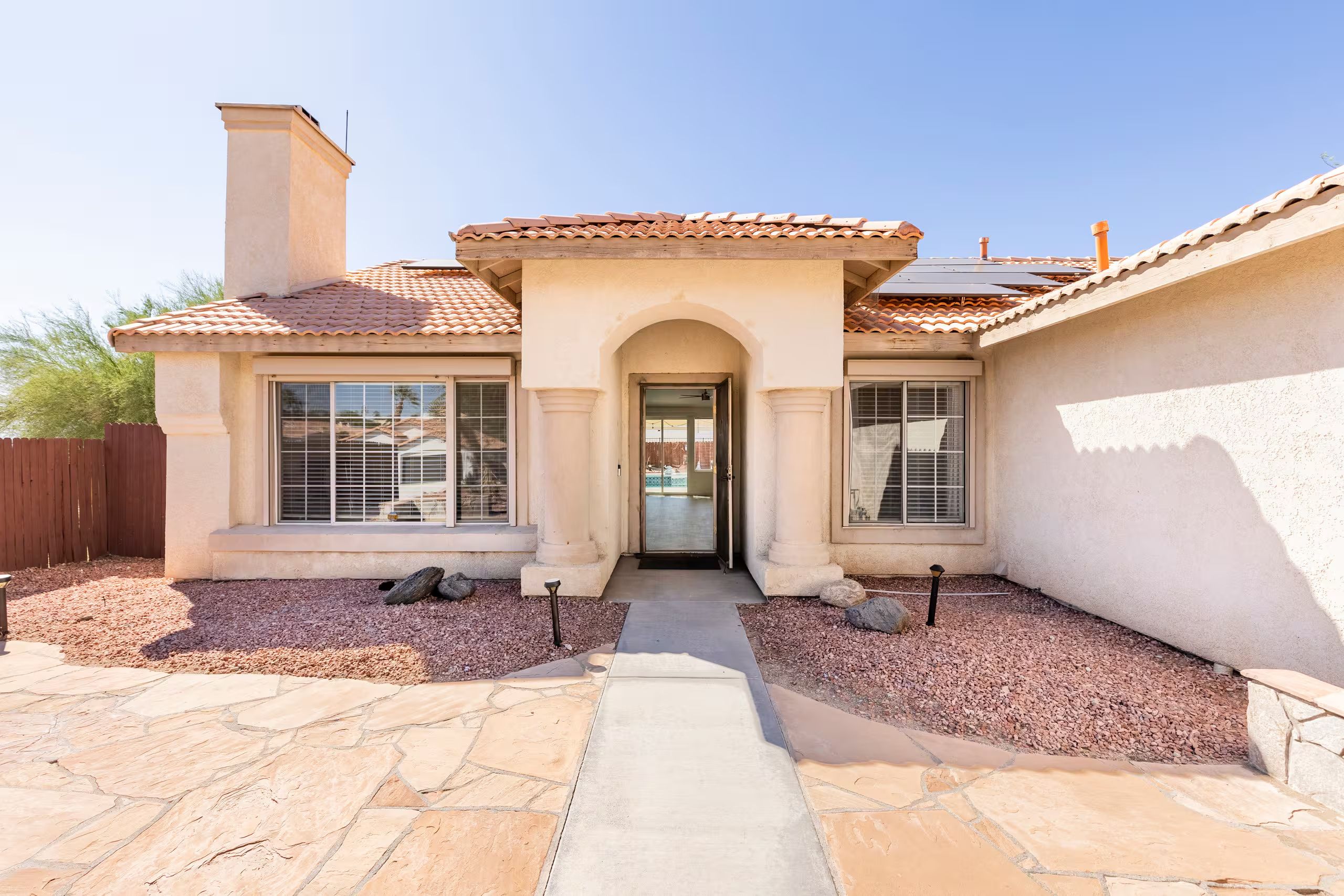 A residential house with a tiled roof, a central entrance, and a stone pathway leading to the door.