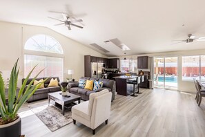 A spacious living area with a kitchen, dining area, and a view of a swimming pool. - Salt Water Pool & Spa with Mountain Sunset Views! (Desert Hot Springs)