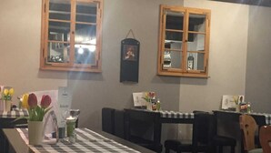 A restaurant with checkered tablecloths, wooden windows, and tulips on the tables. - Double room 2 - Pension Harzer Winkel (Bad Sachsa)