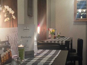 Een restaurantsetting met een geruit tafelkleed, een kaars en een menukaartstandaard.