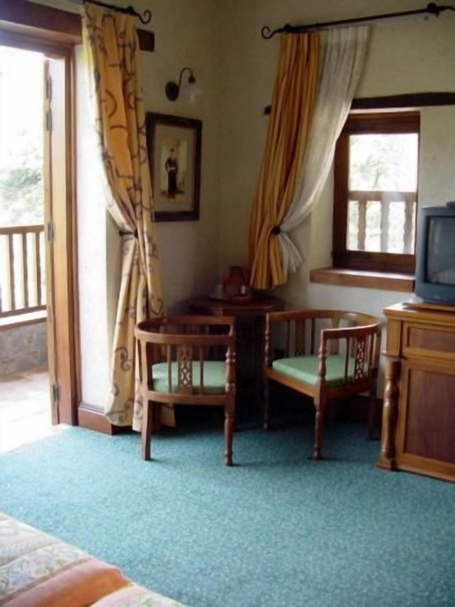 A room with a wooden table and chairs, a television, and a window with curtains.