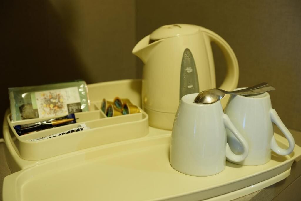 Uma bandeja com uma caneca branca, uma colher e um pequeno recipiente com canetas e um cartão.