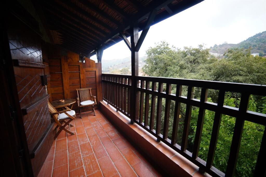 A balcony with a wooden railing, a table, and two chairs.