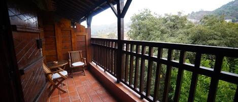 A balcony with a wooden railing, a table, and two chairs.