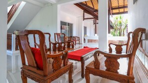 A spacious room with a high ceiling, a wooden dining table with chairs, and a red runner. - OYO 2548 Rasa Sayang Inn (Nusa Dua)