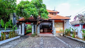 A traditional house with a tiled roof, a tiled entrance, and a paved driveway. - OYO 2548 Rasa Sayang Inn (Nusa Dua)