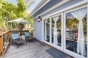 A deck with outdoor furniture, a pergola, and a view of the surrounding landscape. - The Periwinkle House – Bask Poolside at this Sunlit West Palm Retreat (West Palm Beach)